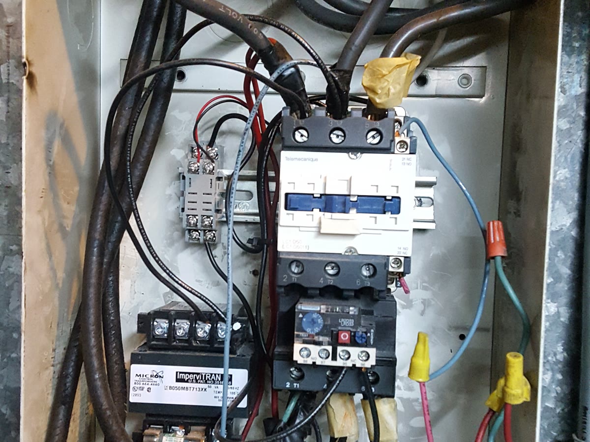 An open control panel with a motor contactor, overload relay, and transformer