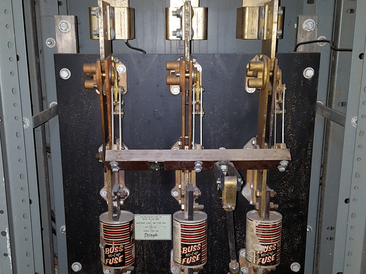 Inside a cabinet of older commercial switchgear with three large fuses